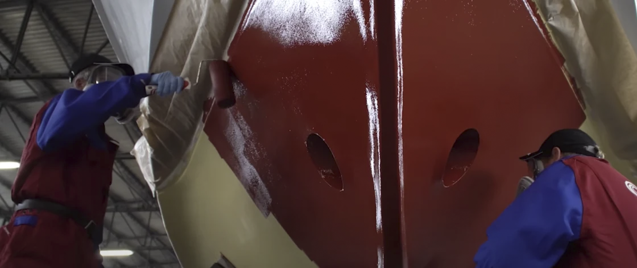 Applying a red Hempel coating to a boat hull